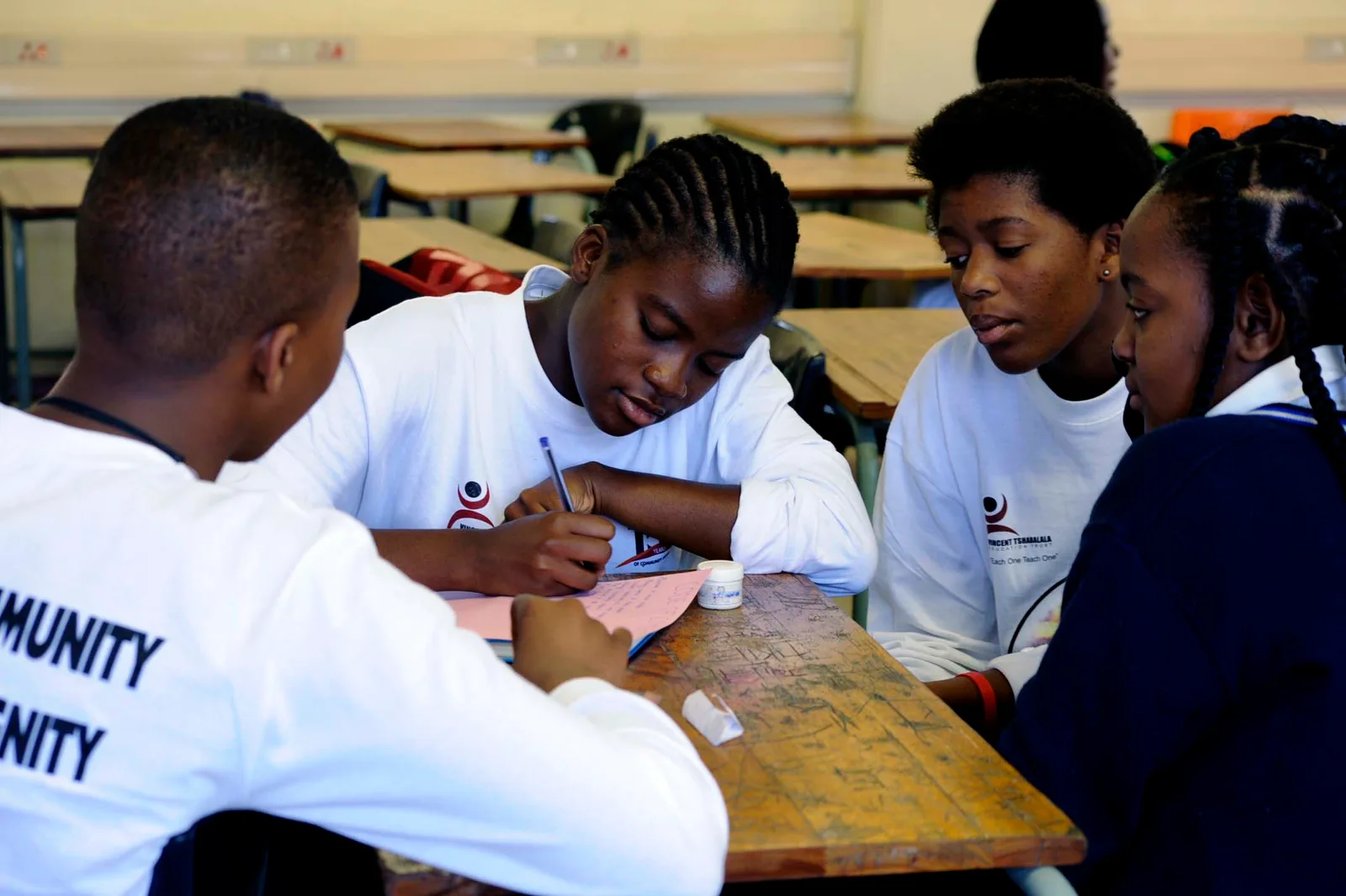 Learners working together around a classroom desk